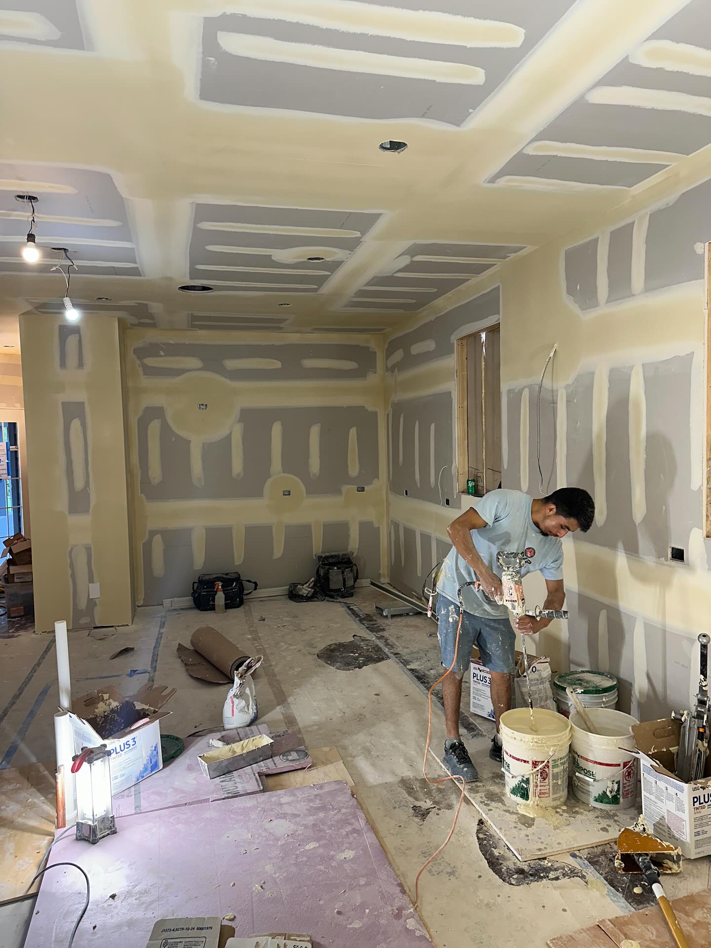 JVP worker spraying joint compound on walls