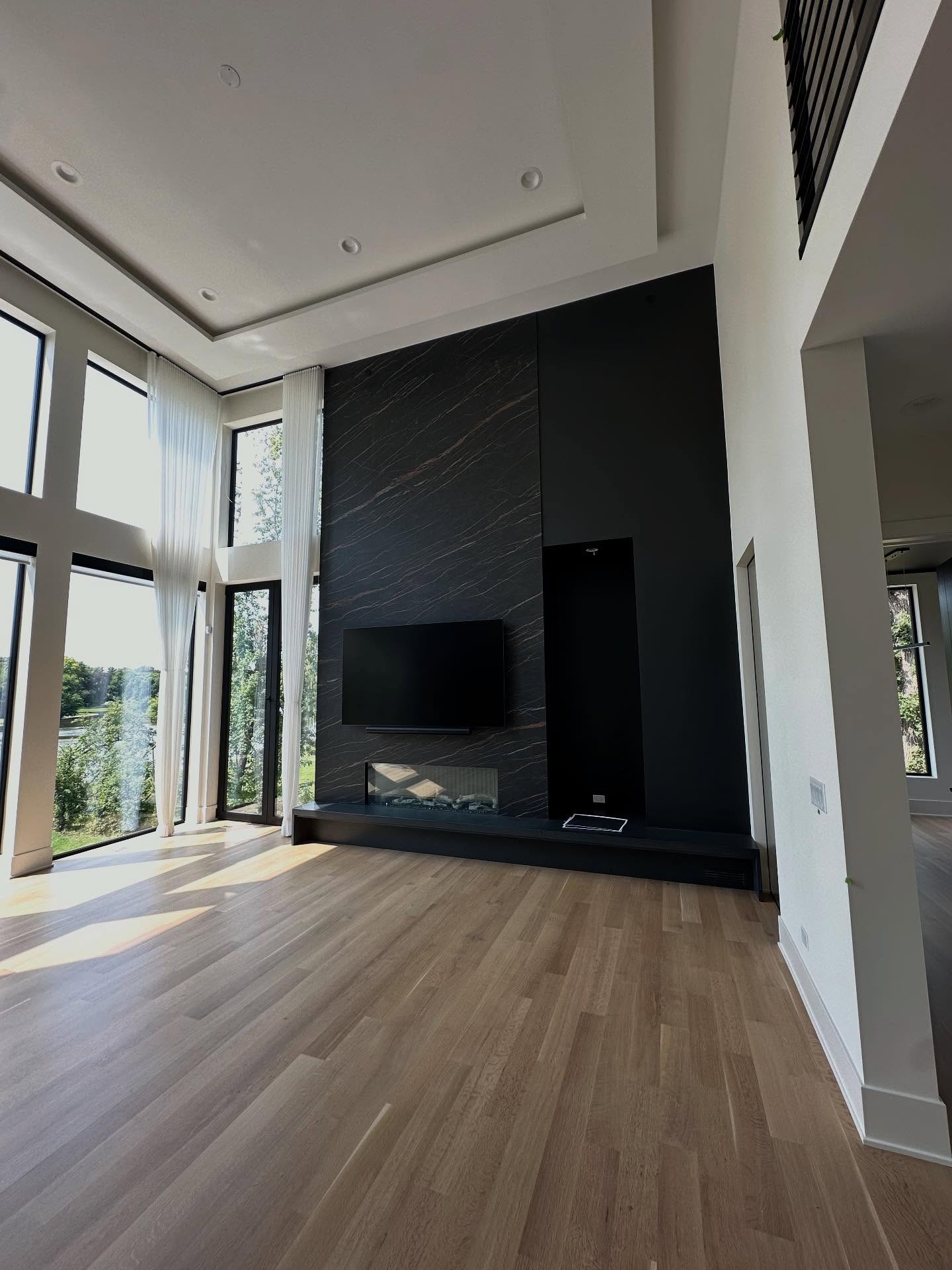 Double-height living room with black marble fireplace and tray ceiling