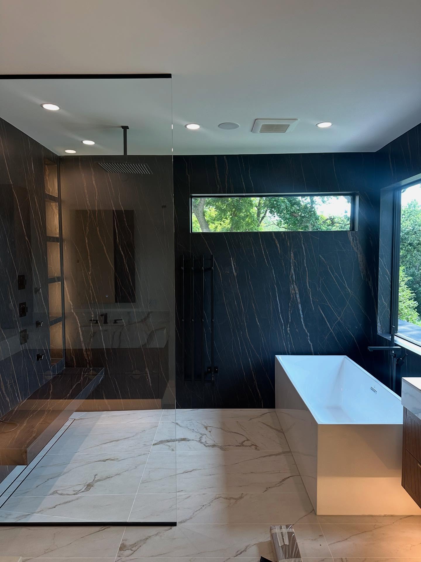 Dark marble master bathroom with rain shower and freestanding tub